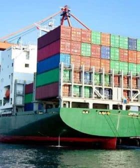 Large container ship loaded with colorful shipping containers at a dock. - Olive Oil Times