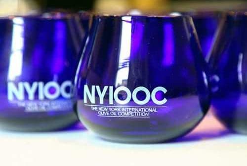 Set of blue glasses featuring the logo of the New York International Olive Oil Competition. - Olive Oil Times