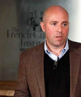 A man in a brown blazer speaking at the French Cultural Institute with a microphone attached. - Olive Oil Times