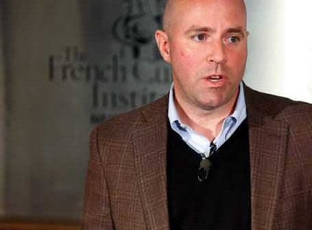 A man in a brown blazer speaking at the French Cultural Institute with a microphone attached. - Olive Oil Times