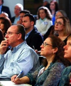 A diverse group of individuals attentively listening during a conference presentation. - Olive Oil Times