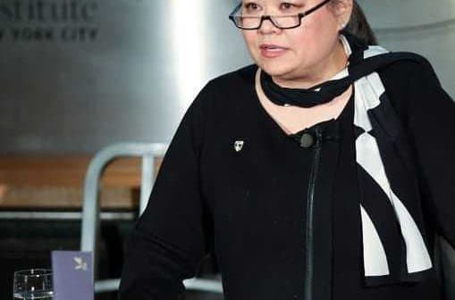 Woman wearing glasses and a black outfit speaking at a podium during an event at the Culinary Institute of America. - Olive Oil Times