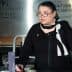 Woman wearing glasses and a black outfit speaking at a podium during an event at the Culinary Institute of America. - Olive Oil Times