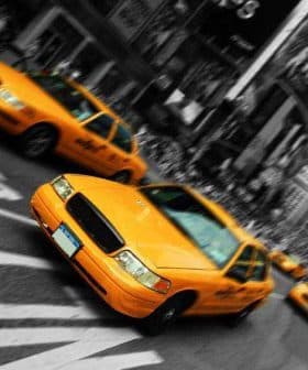 Yellow taxi cabs driving through a busy intersection in a city setting. - Olive Oil Times