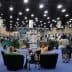 Exhibition hall with attendees seated in chairs and various displays in the background. - Olive Oil Times