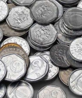 A collection of various Czech coins arranged in a disordered pile on a flat surface. - Olive Oil Times