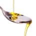 Olive oil being poured from a bottle into a stainless steel spoon. - Olive Oil Times