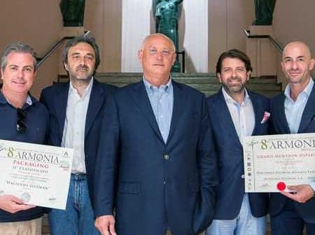 Five individuals posing together at an event, holding certificates in front of a sculpture backdrop. - Olive Oil Times