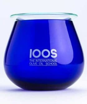 Blue glass container with the logo of The International Olive Oil School printed on it. - Olive Oil Times