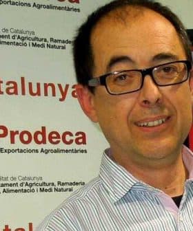 Man wearing glasses smiling at an event with Prodeca branding in the background. - Olive Oil Times