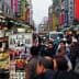 Crowd of people walking through a bustling street market in Taiwan with various stalls and signage. - Olive Oil Times