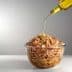 A glass bowl filled with cereal being drizzled with olive oil from a bottle. - Olive Oil Times
