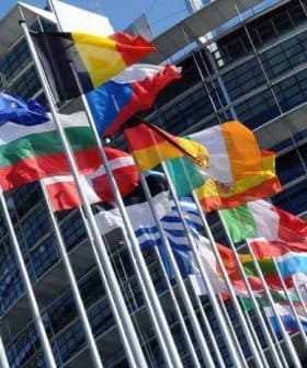 Various national flags of European countries displayed outside the European Parliament building. - Olive Oil Times