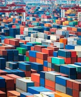 Aerial view of numerous shipping containers stacked in various colors at a port facility. - Olive Oil Times