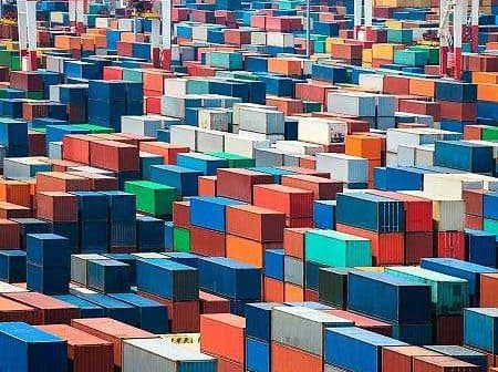 Aerial view of numerous shipping containers stacked in various colors at a port facility. - Olive Oil Times