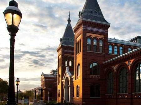 Red brick building with pointed towers and large windows under a cloudy sky. - Olive Oil Times
