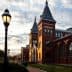 Red brick building with pointed towers and large windows under a cloudy sky. - Olive Oil Times