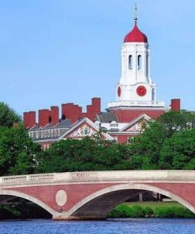 Harvard University building featuring a red dome and clock tower, viewed from across the river. - Olive Oil Times