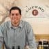 Man in a checkered shirt standing behind a counter at Lucero Olive Oil Company. - Olive Oil Times
