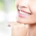 Close-up of a woman's face showing a smile with white teeth and clear skin. - Olive Oil Times