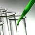 Green liquid being dropped into a glass test tube with a pipette. - Olive Oil Times