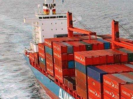 A large container ship with stacked cargo containers navigating through the ocean. - Olive Oil Times