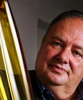 Man with a serious expression holding three bottles of olive oil. - Olive Oil Times