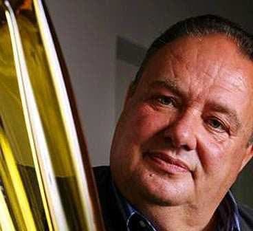 Man with a serious expression holding three bottles of olive oil. - Olive Oil Times