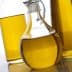 Glass cruet filled with olive oil, surrounded by two additional bottles of oil. - Olive Oil Times