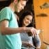 A man and a woman pouring olive oil while cooking in a kitchen setting. - Olive Oil Times