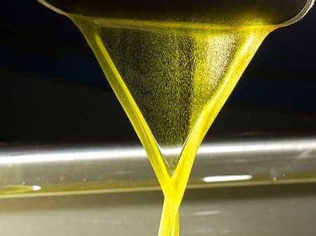 Stream of golden olive oil pouring from a spout into a container. - Olive Oil Times