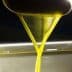 Stream of golden olive oil pouring from a spout into a container. - Olive Oil Times
