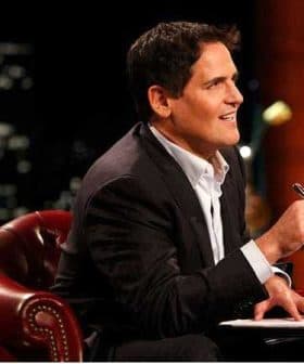 A man in a suit sitting on a leather chair, holding a pen and looking thoughtfully. - Olive Oil Times