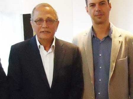 Two men standing side by side, both wearing formal attire, with one in a dark suit and the other in a light-colored blazer. - Olive Oil Times