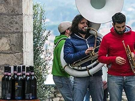 Three musicians performing outdoors with a tuba, trumpet, and other instruments. - Olive Oil Times