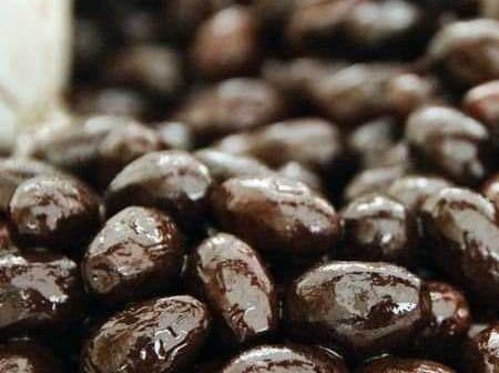 Close-up view of shiny black olives displayed in a natural setting. - Olive Oil Times