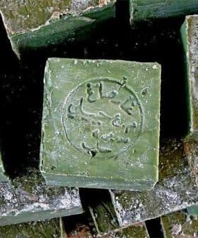 Stack of Aleppo soap bars with a stamped logo on the top bar. - Olive Oil Times