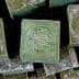 Stack of Aleppo soap bars with a stamped logo on the top bar. - Olive Oil Times