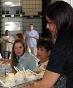 A woman serving ice cream from a tray to attendees at a gathering or event. - Olive Oil Times