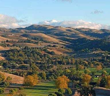A scenic view of rolling hills in California with trees and a clear sky. - Olive Oil Times