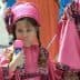 Young girl wearing a pink traditional costume holding a colorful toy in her hand. - Olive Oil Times