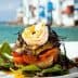 A layered dish featuring shrimp, vegetables, and greens presented on a plate. - Olive Oil Times