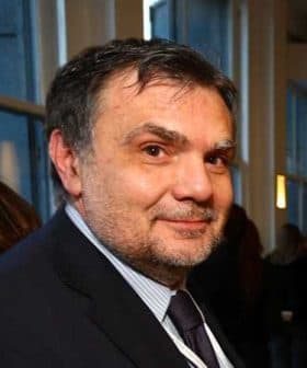 A man with short hair wearing a suit and tie, looking towards the camera with a neutral expression. - Olive Oil Times