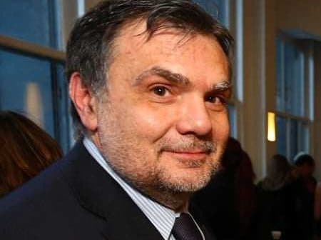 A man with short hair wearing a suit and tie, looking towards the camera with a neutral expression. - Olive Oil Times