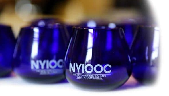 Blue glasses with the NYIOOC logo for the New York International Olive Oil Competition. - Olive Oil Times