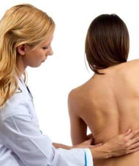 Healthcare professional examining the back of a patient in a clinical setting. - Olive Oil Times