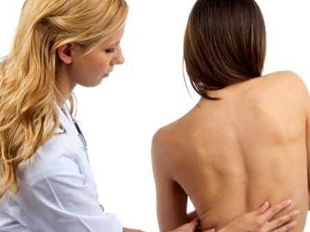 Healthcare professional examining the back of a patient in a clinical setting. - Olive Oil Times