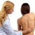 Healthcare professional examining the back of a patient in a clinical setting. - Olive Oil Times