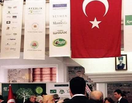 Turkish flag with a white star and crescent displayed at an indoor event with attendees. - Olive Oil Times