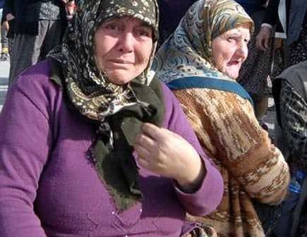 Two women wearing headscarves, one with a distressed expression and the other looking away. - Olive Oil Times